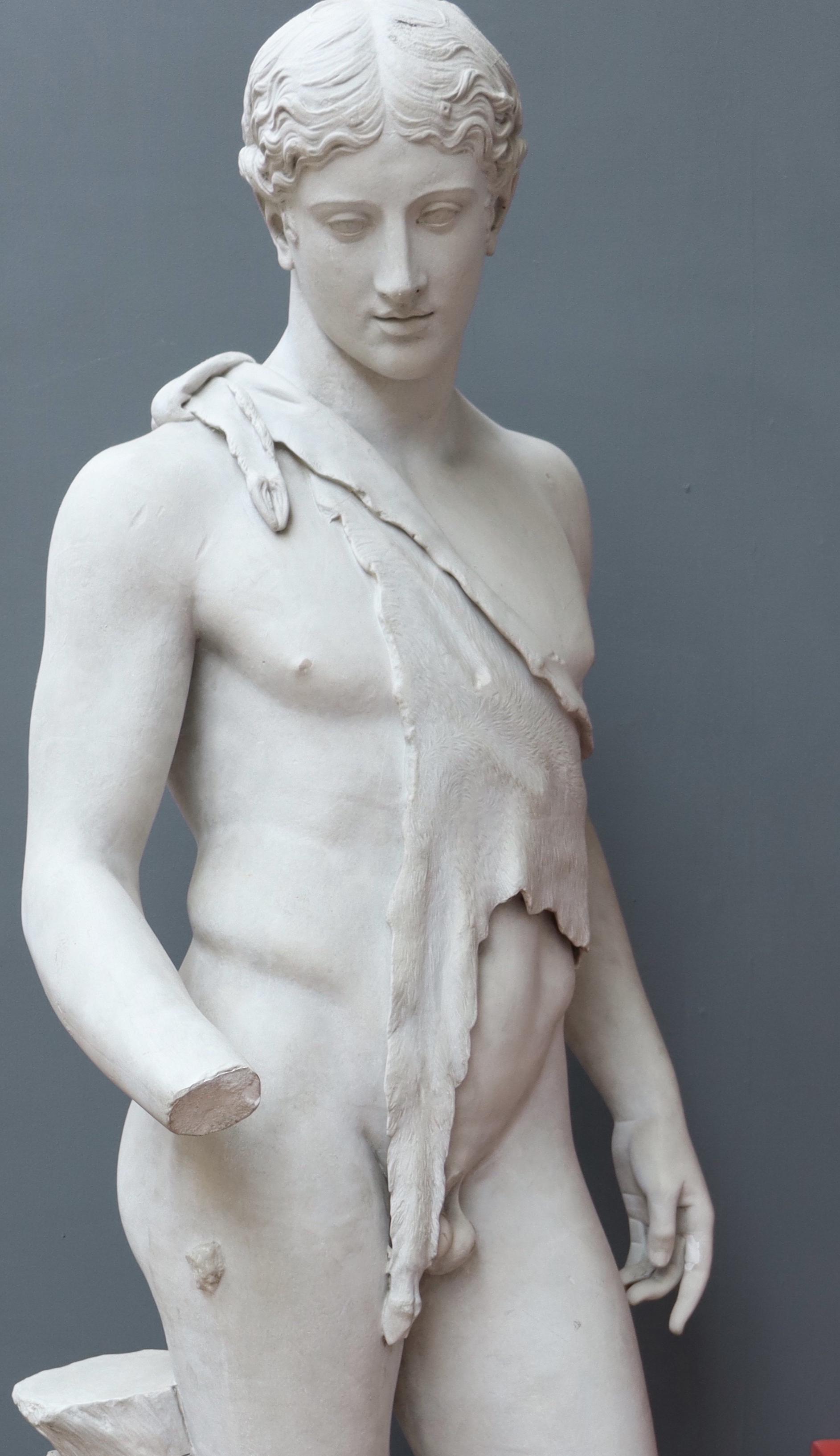 Plaster cast figure of a young man wearing only an animal skin draped over his naked chest